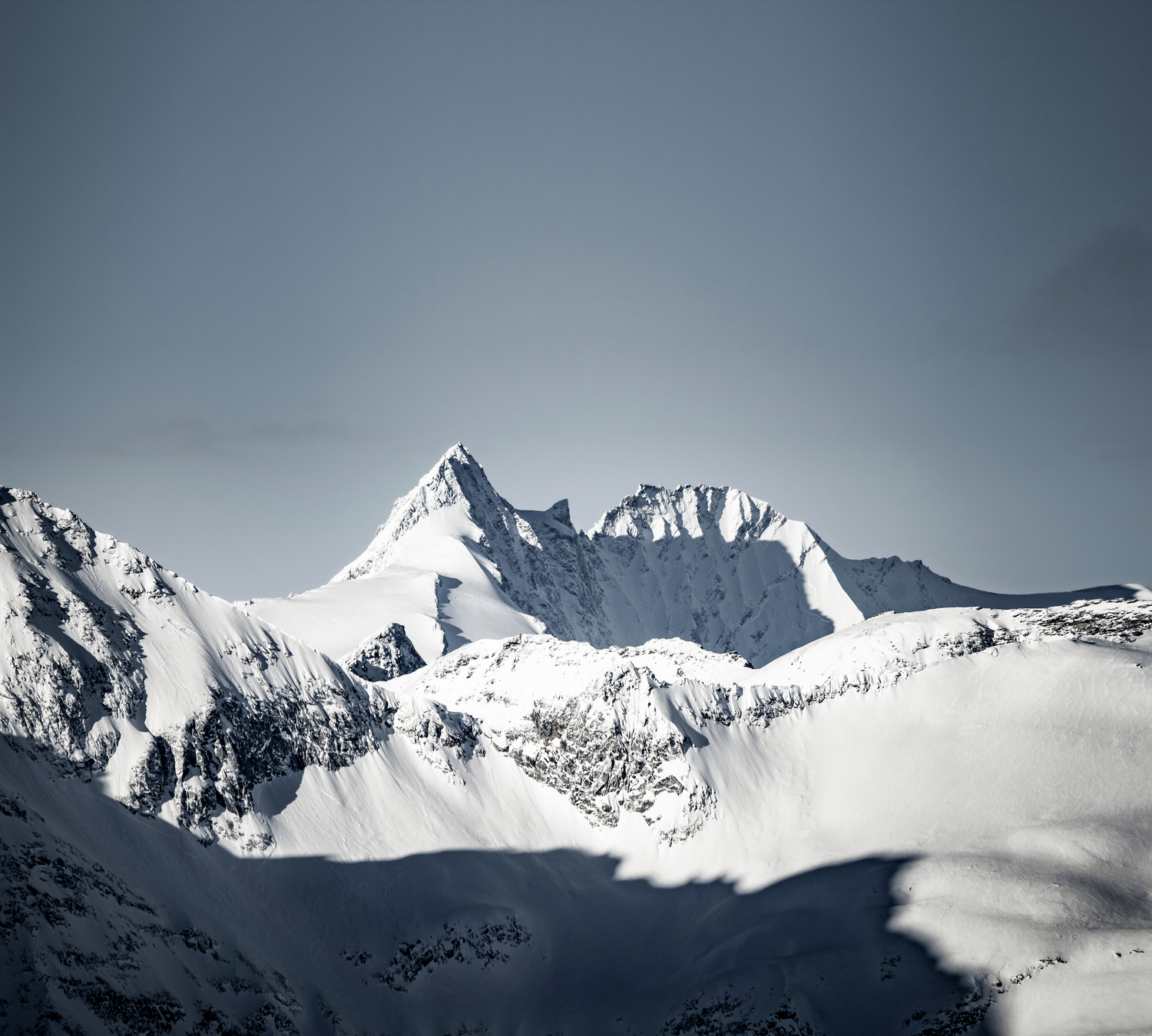 Schneebedeckter Gipfel des Großglockners mit markanter Spitze und umliegenden Berghängen im Sonnenlicht.