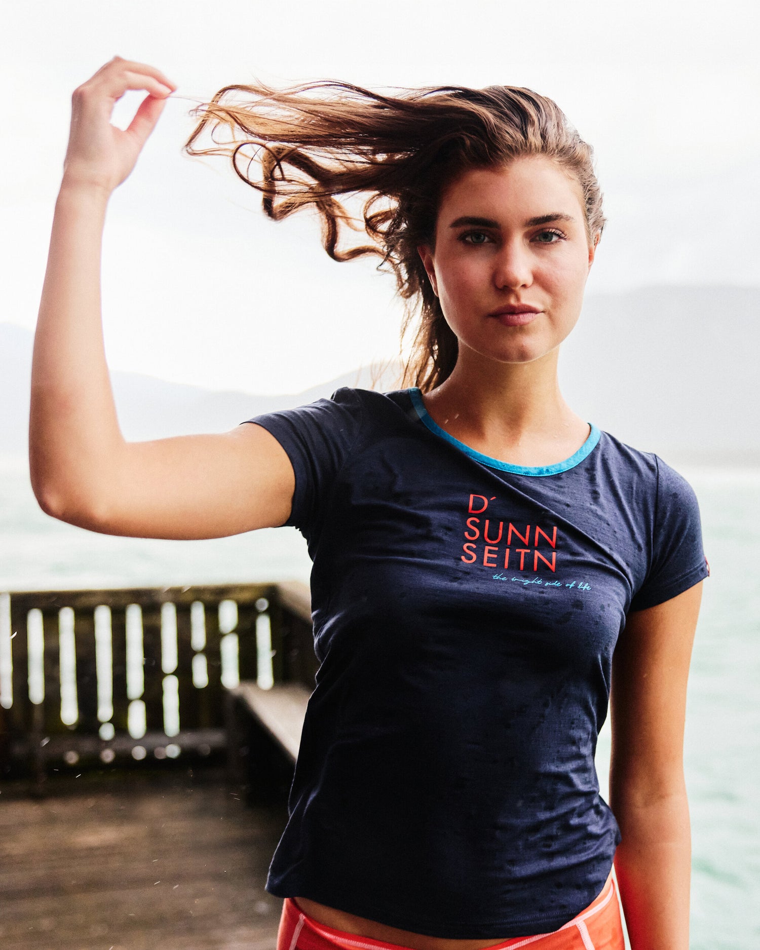 Frau mit nassem dunkelblauem T-Shirt ‚D’ Sunn Seitn‘ von Ein schöner Fleck Erde am Seeufer