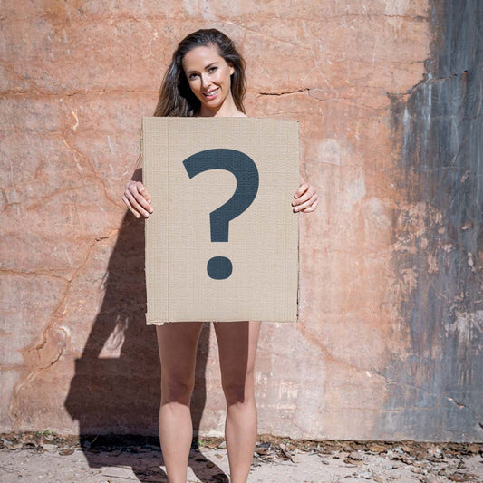 Überraschungsbox Damen – Frau hält Kartonschild mit Fragezeichen, Produktüberraschung von Ein schöner Fleck Erde